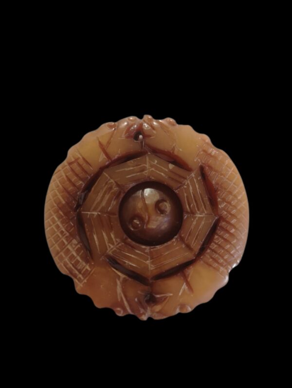 4.8 cm x 5 mm x 25 g Un pendentif puissant et spectaculaire, réunissant dragons protecteurs, équilibre Yin-Yang et Bagua, pour créer un talisman complet : protecteur, harmonisant et chargé de sens. Ce pendentif en jade fumé présente une sculpture et une symbolique exceptionnelles : une boule intérieure mobile, entourée du motif du Bagua et protégée par quatre têtes de dragons soigneusement sculptées. Sa forme circulaire évoque l’harmonie du Yin-Yang, tandis que les trigrammes gravés renforcent son énergie symbolique. Les quatre dragons : en Chine, le dragon est symbole de puissance, de chance, de protection et d’ascension spirituelle. Les quatre directions qu’ils incarnent créent un cercle de protection totale, évoquant les quatre gardiens célestes et la maîtrise des forces du monde. Yin-Yang : équilibre des forces opposées, harmonie intérieure, circulation fluide de l’énergie. Bagua (八卦) : les huit trigrammes représentent les énergies fondamentales de l’univers, favorisant protection, Feng Shui, et équilibre du Qi. Boule captive : symbole d’unité, d’âme préservée et de maîtrise artisanale. • Apporte protection énergétique et chance • Équilibre les émotions et renforce la stabilité intérieure • Favorise la clarté mentale et une circulation harmonieuse du Qi • Procure apaisement grâce au mouvement doux de la boule centrale